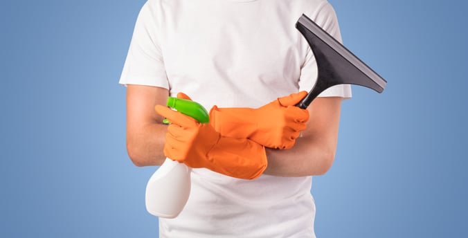 Housekeeper with cleaning product and equipment in front of a blue empty wall