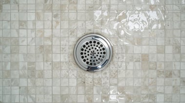 a tiled shower showing a circular drain. the shower floor is full of water.